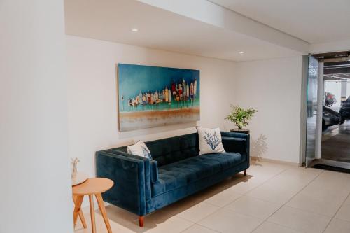 阿拉沙Apartamentos de Temporada Araxá WIFI GRATUITO - ESPAÇO HOME OFFICE的客厅配有蓝色沙发和绘画作品