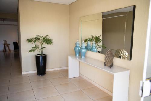 阿拉沙Apartamentos de Temporada Araxá WIFI GRATUITO - ESPAÇO HOME OFFICE的走廊上设有镜子和蓝色花瓶