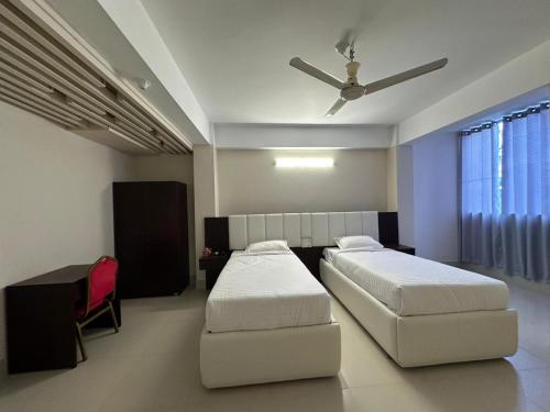 巴里沙尔Hotel Kingfisher - Barishal的一间卧室配有两张床和吊扇