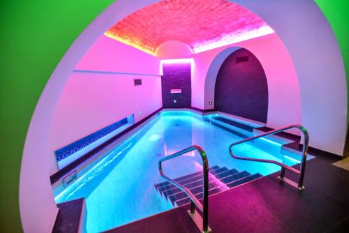 罗马THE ONE Boutique Hotel & SPA Rome的拥有紫色和绿色灯光的室内游泳池