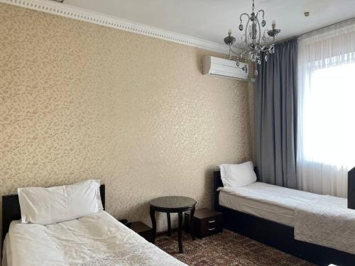 比什凯克Sultan的客房设有两张床、一张桌子和一扇窗户。
