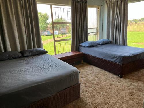 BrakpanKharimbi Campsite House的两张床位于带窗户的房间内