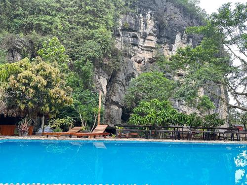 宁平Tam Coc Rocky Hotel的一座蓝色的游泳池,后面是一座山