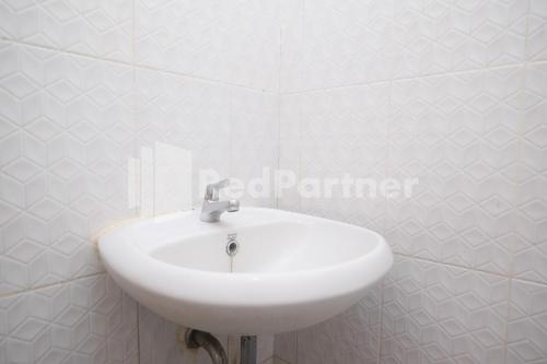 三宝垄Griya Loka 2 Syariah Near Simpang Lima Mitra Reddoorz的浴室设有白色瓷砖墙壁,配有白色水槽