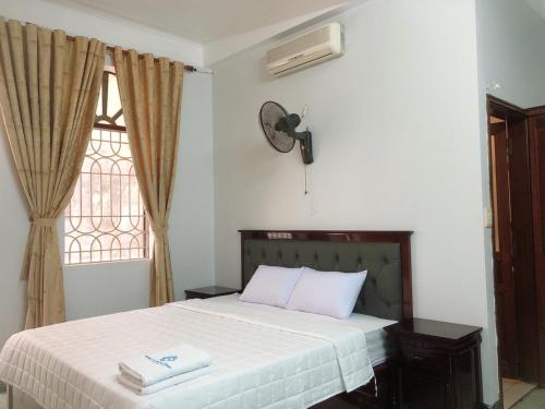 海防Hotel Nam Sơn Tân Dương的一间卧室配有一张带白色床单的床和一扇窗户。