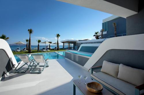 库基尼坎尼奥Arina Beach Resort的房屋旁的游泳池配有长沙发和椅子