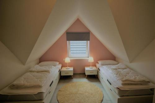 勒伯尔K 100 OG - charmante Ferienwohnung für die ganze Familie in Röbel an der Müritz的阁楼卧室设有两张床和窗户。