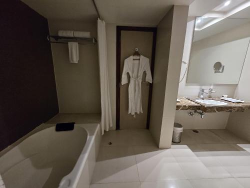 古瓦哈提Hotel Daaysco Oley Allo的浴室配有浴缸旁的浴袍