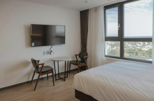西归浦市Lemain Hotel Seogwipo的一间卧室配有一张床、一张桌子和一台电视。