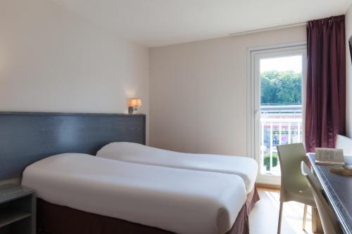 安德纳斯The Originals City, Hôtel Le Louisiane, Belfort Sud (Inter-Hotel)的配有窗户的酒店客房内的两张床