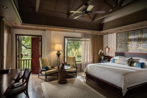 湄林Four Seasons Resort Chiang Mai的卧室配有一张床和一张桌子及椅子
