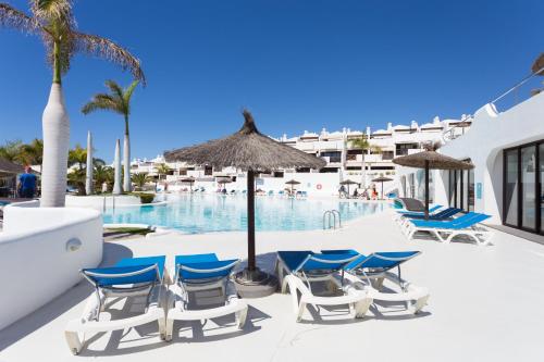 帕莱索海滩Paradise Homes Tenerife的一组椅子和遮阳伞,位于游泳池旁