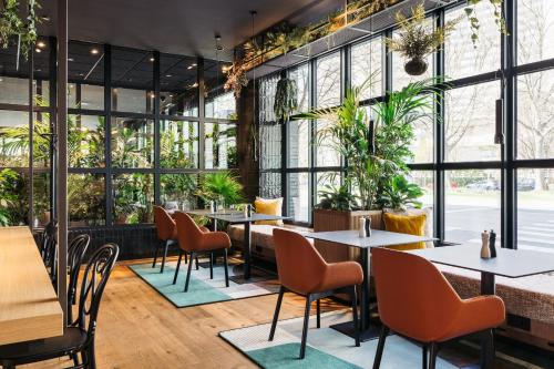维也纳Hotel Schani Uno City的一间设有桌椅的餐厅,种植了植物