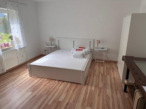 Ferienwohnung Hinzweiler的白色卧室设有白色的床和木地板