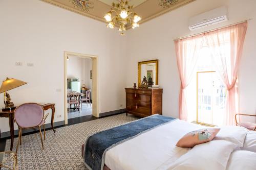 拉古萨Palazzo d'Autore - Luxury Home - Ragusa Centro的一间卧室配有一张床、一张书桌和一个窗户。