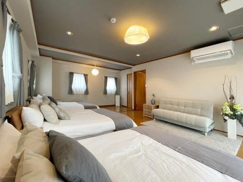 广岛bHOTEL M bld - Beautiful, spacious apartment next to Peace Park的一间带两张床和一张沙发的大卧室