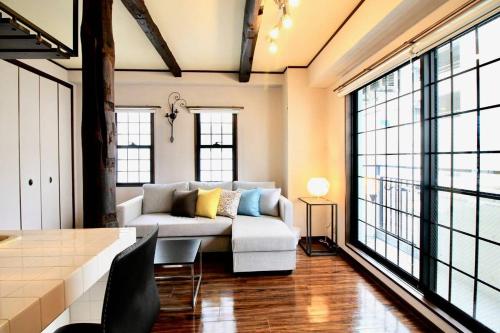 广岛bHOTEL Pacifica - 30sec walk to PeacePark, Beautiful Condo的带沙发的客厅和部分窗户。