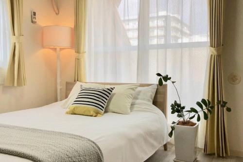 广岛bHOTEL La-Shante - 5 mins walk to the PeacePark & Up to 4 ppl的一间卧室配有一张带白色床单的床和一扇窗户。