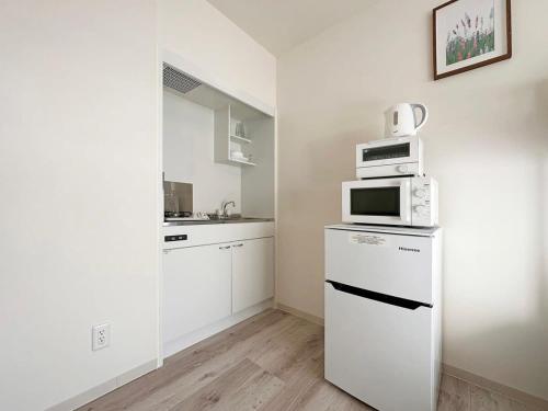 尾道市bHOTEL Yutori - Attractive 1Br Apt for 4 people in Onomichi的白色的厨房配备了微波炉和冰箱。