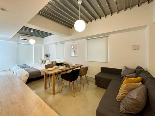 广岛bHOTEL Arts Dobashi - Cozy & Modern Studio Apt 5 Mins Walk to Peace Park的带沙发、床和桌子的客厅