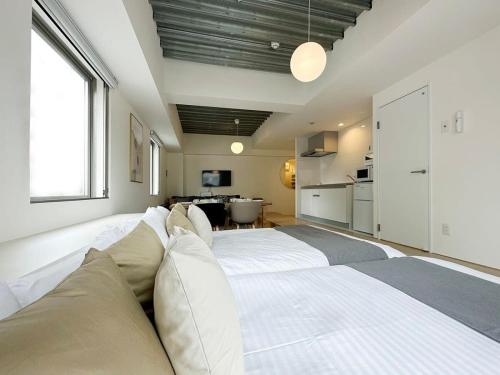 广岛bHOTEL Arts Dobashi - Cozy & Modern Studio Apt 5 Mins Walk to Peace Park的带厨房的客房内一张大白色的床