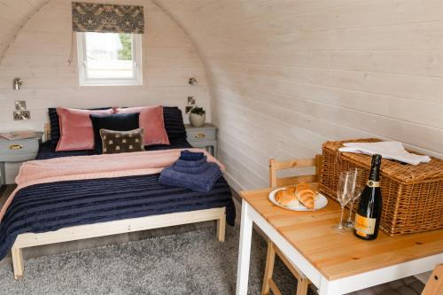 FindonThe Downs Stables Glamping Pod Theos Charm的一间卧室配有一张床和一张桌子及一瓶葡萄酒