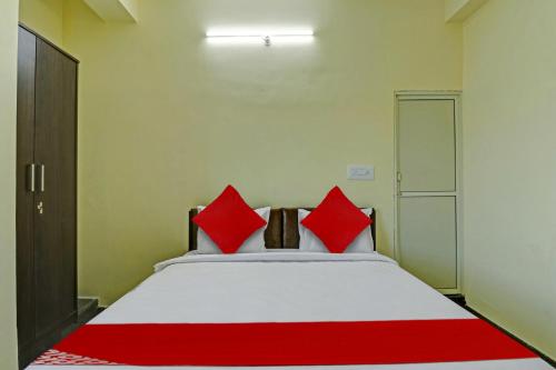 班加罗尔OYO Flagship Sri Chamundeshwari Boarding And Lodge的一间卧室配有一张带红色枕头的大床
