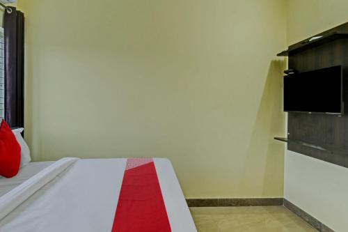 班加罗尔OYO Flagship Sri Chamundeshwari Boarding And Lodge的卧室配有一张床,墙上配有电视。