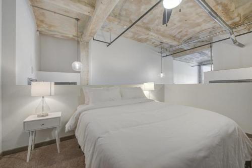 堪萨斯城2BR 2BA Spacious Historic Loft With Gym by ENVITAE的白色卧室设有一张大床和一盏灯。