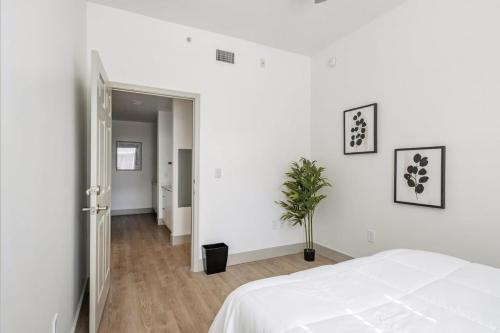 夏洛特4B 3BA Premium Family Apartment with Gym的一间白色的卧室,配有床和盆栽植物