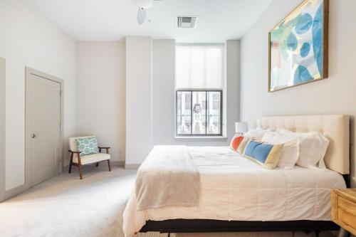 巴尔的摩2BR Distinguished Apartment Rooftop Deck & Gym的白色卧室配有一张大床和椅子