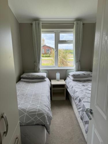 瑟斯克Meadow View Lodge at Hollin Barn Lodge park Thirsk,North Yorks的带窗户的客房内的两张床