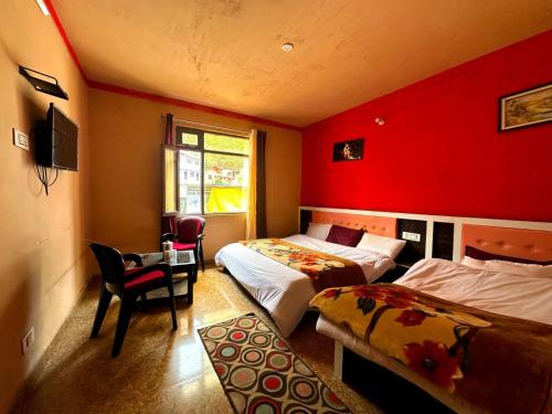 巴德里纳特Badrinath Guest House的一间卧室设有两张床和红色的墙壁