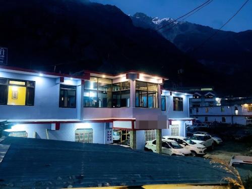 巴德里纳特Badrinath Guest House的一座有汽车在晚上停在停车场的建筑