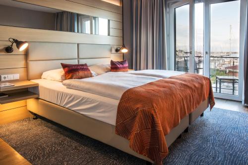 海利根港海洋时代海港酒店的一间卧室设有一张大床和一个大窗户