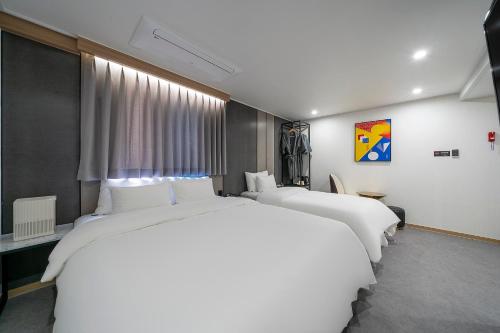 堤川市Number 25 Hotel Jecheon的窗户客房内的两张大型白色床