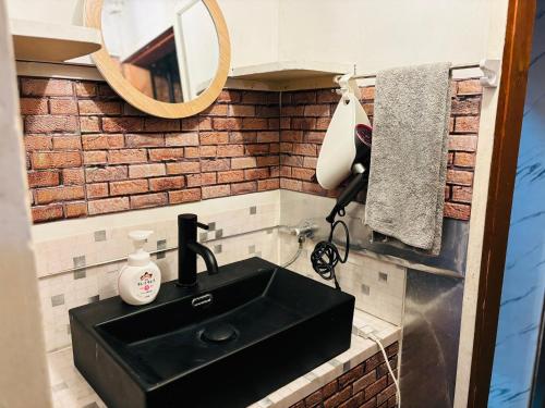 汤河原町温泉街の入り口にあるゲストハウス SLOW HOUSE yugawara的浴室设有黑色水槽和镜子