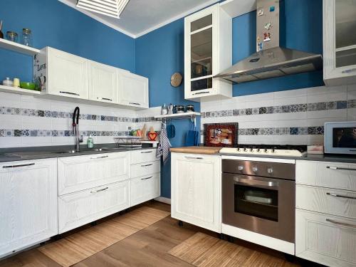 维亚雷焦Appartamento piano terra centro的厨房配有白色橱柜和蓝色的墙壁