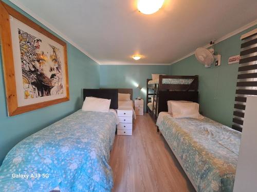 奇廉HOSTAL EL AROMO☆的卧室设有两张床,拥有绿色的墙壁和木地板