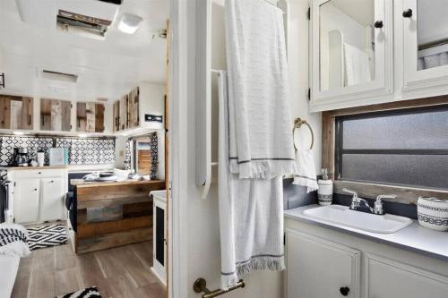 双子瀑布#StayinMyDistrict Twin Falls Backyard Glamper的厨房配有白色橱柜、水槽和窗户。