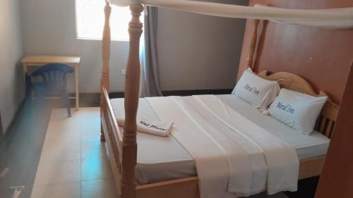 金贾Meral inn Jinja的卧室配有带白色床单和枕头的天蓬床。