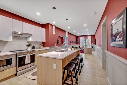 纳什维尔Nashville - 635 7th Ave S Unit 412的一间带红色墙壁的厨房和一个带凳子的厨房岛