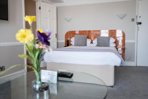 布莱顿霍夫莱恩斯酒店的一间卧室,配有一张床和花瓶