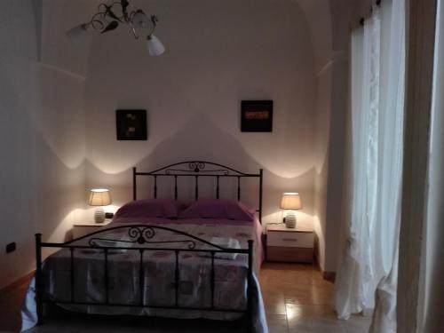 曼杜里亚Il melograno b&b的一间卧室配有一张带紫色枕头的床和两盏灯。
