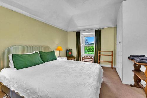 East LintonFinest Retreats - The West Wing at The Mill House的一间卧室配有一张带绿色枕头的床和一扇窗户