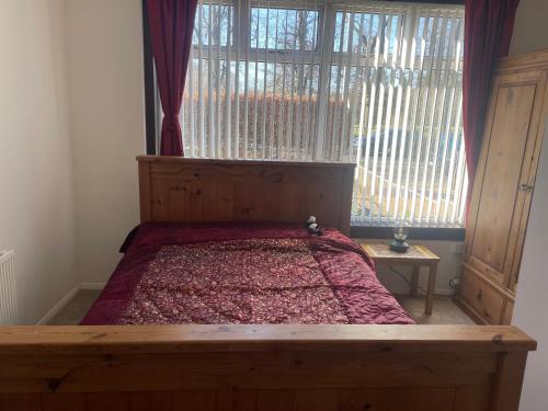 格拉斯哥Homestay的一间卧室设有一张木床和大窗户