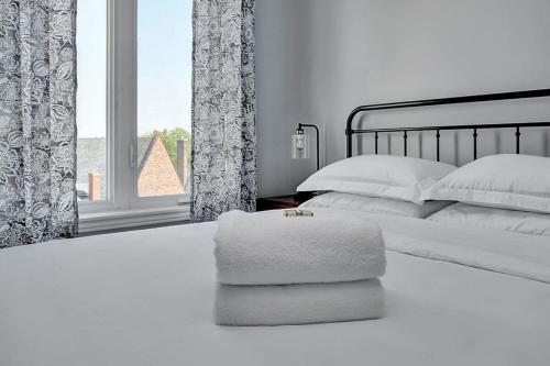 金斯顿High-end condo downtown Kingston near RMC Queens的白色卧室配有带枕头的床和窗户
