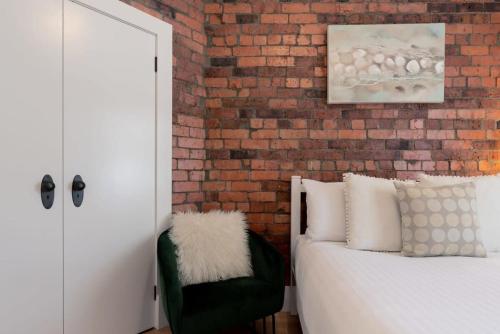 朗塞斯顿Cosy Accommodation Moments From The Centre Of Town with Wifi的卧室设有砖墙、一张床和一把椅子