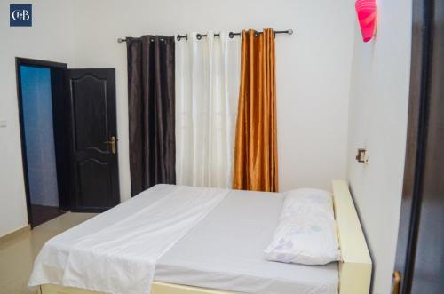 Abomey-CalaviCOMPLEXE HOTELIER LA BONTE ( CHB )的卧室配有白色的床和橙色窗帘