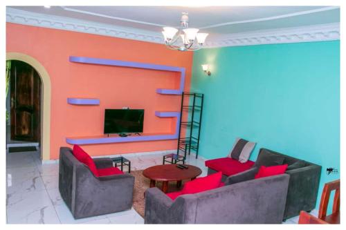 BafoussamRésidences K and D的客厅配有红色椅子和电视